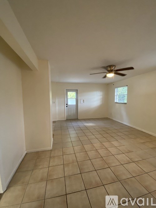 A spacious room with a ceiling fan and tiled flooring.