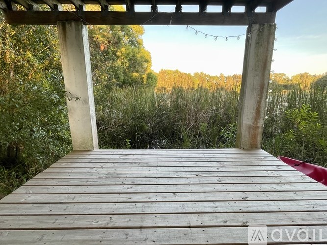 A wooden deck with a red object on the right side and string lights hanging from the roof.