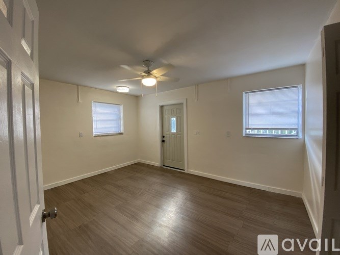 A room with a ceiling fan and two windows.