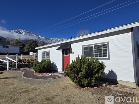 A white mobile home with a red door and a small garden in front.