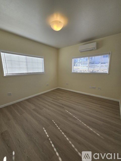 A room with wooden flooring and a window with blinds.