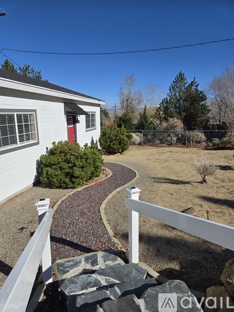 A white house with a red door and a gravel pathway leading to it.