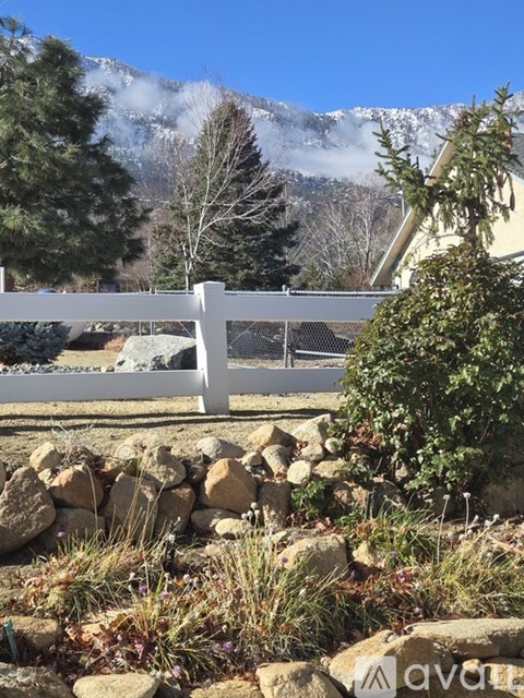 A white fence in front of a mountain.