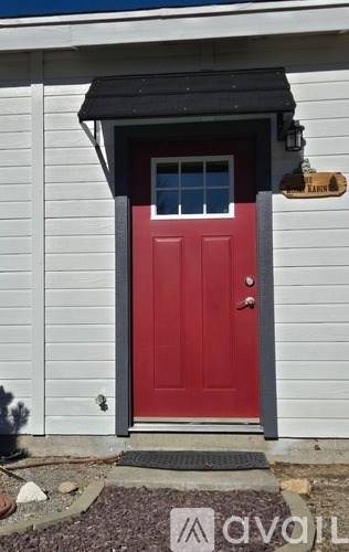 A red door with a black awning and a wooden sign above it.