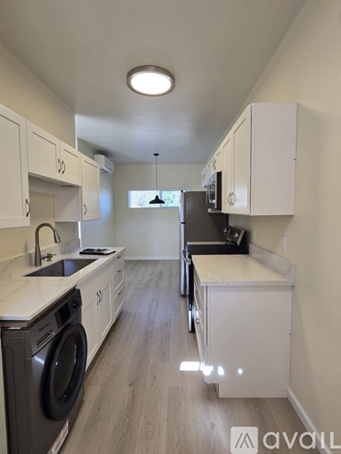 A modern kitchen with white cabinets and a washing machine.