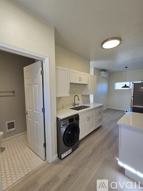 A kitchen with a washing machine in the doorway.