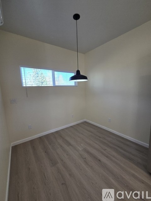 A room with wooden flooring and a hanging light fixture.