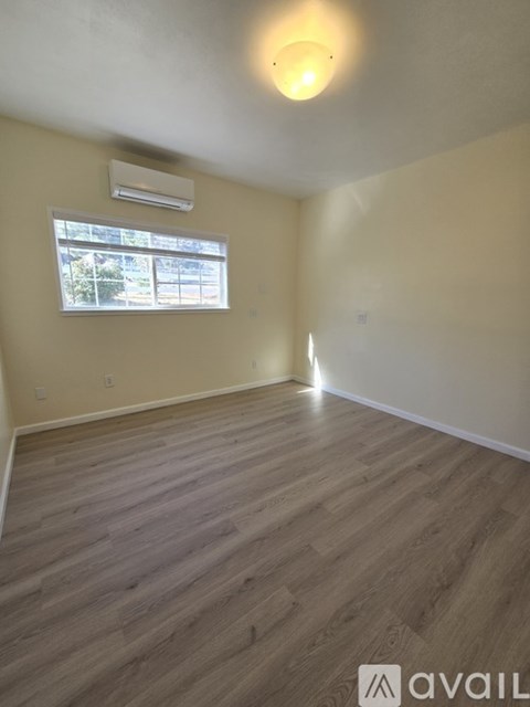 A room with wooden flooring and a window with blinds.