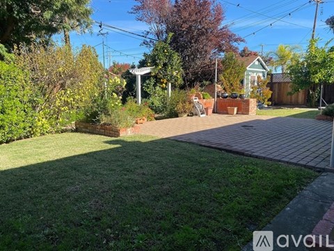A backyard with a lawn, a fence, and a small house in the background.