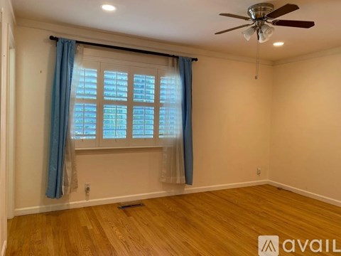 A room with a ceiling fan and a window with blue curtains.
