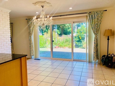 A room with a chandelier, sliding glass doors, and a lamp.
