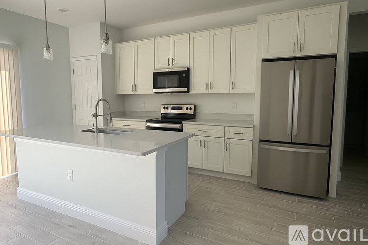 A kitchen with white cabinets and a stainless steel refrigerator.