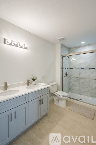 A bathroom with a glass shower stall and a toilet.