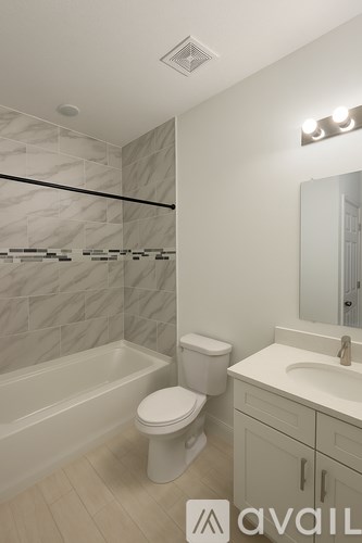 A bathroom with a marble tile shower, white toilet, and a sink with a vanity.