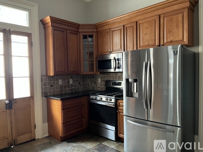 A kitchen with wooden cabinets and a stainless steel refrigerator.