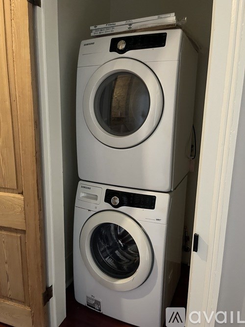 Two white front loading washing machines stacked on top of each other.
