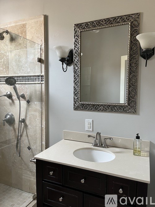 A bathroom with a sink, mirror, and shower.
