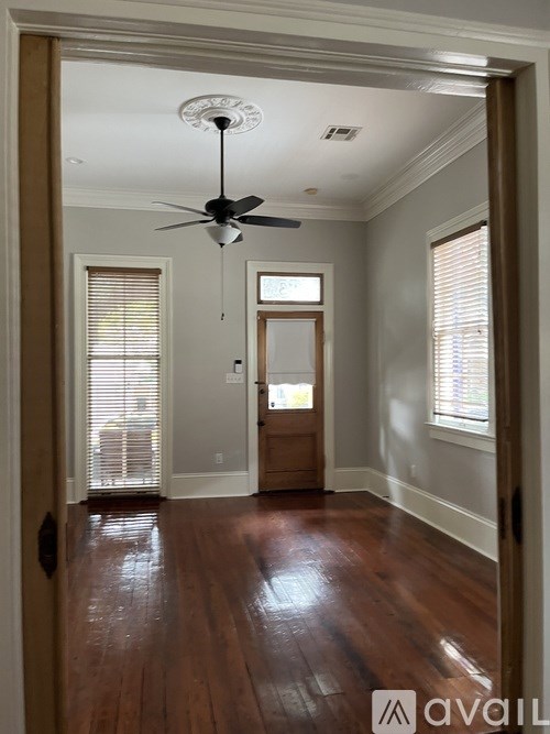 A room with a ceiling fan and wooden floors.