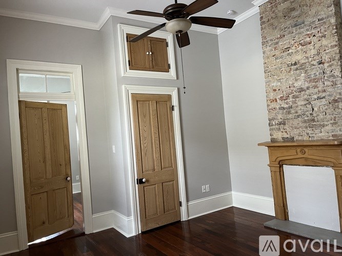 A room with a ceiling fan and a fireplace with a brick wall on the side.