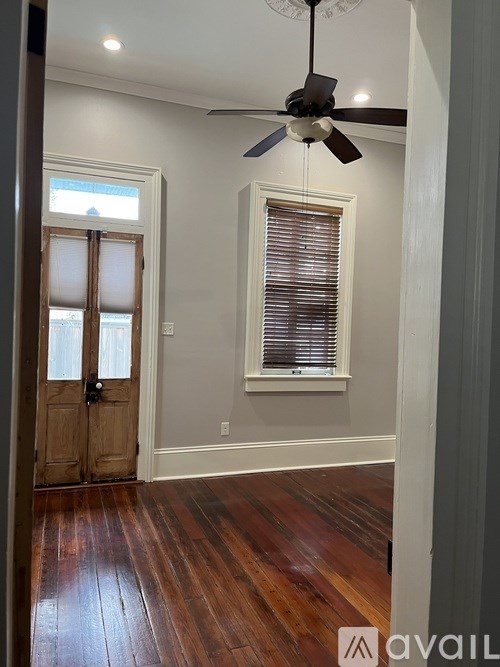 A room with a ceiling fan and wooden floors.