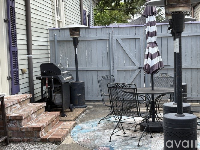 A patio with a table, chairs, and an umbrella.