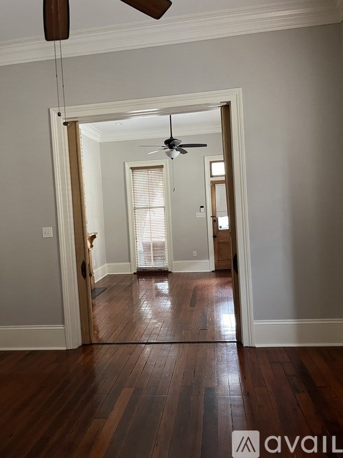 A room with a ceiling fan and wooden floors.