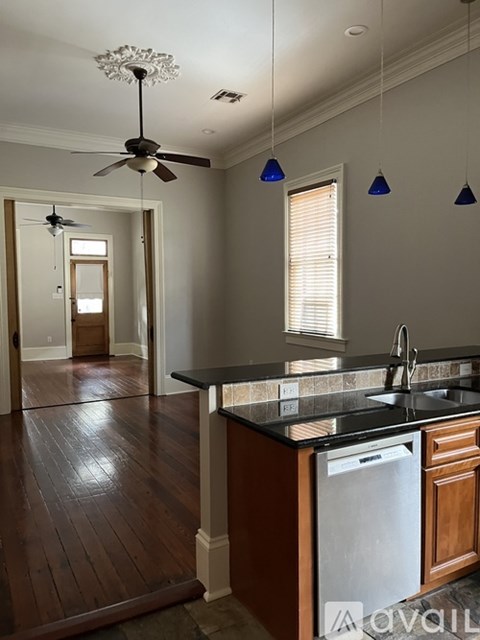 A kitchen with a black counter top and wooden floors.