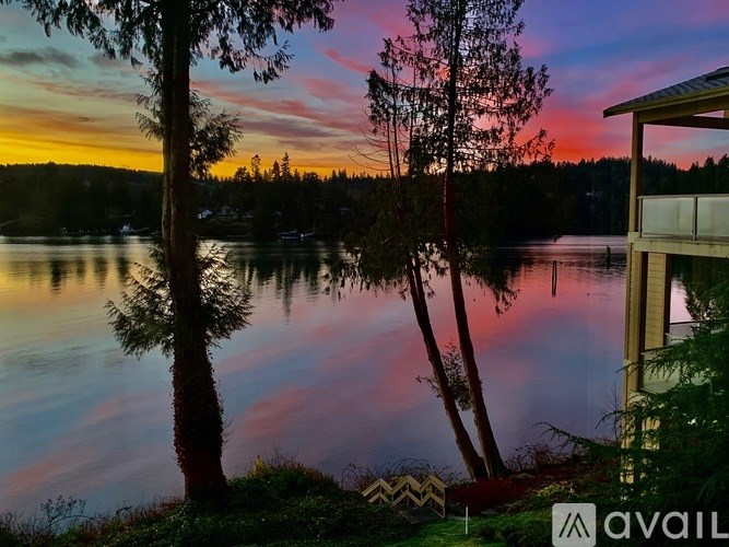A serene lake surrounded by trees with a house on the right side.