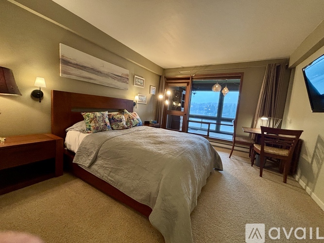 A bedroom with a large bed and a window overlooking a snowy landscape.