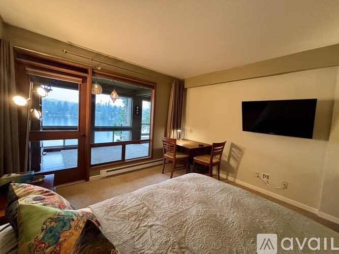 A bedroom with a large bed and a flat-screen TV mounted on the wall.