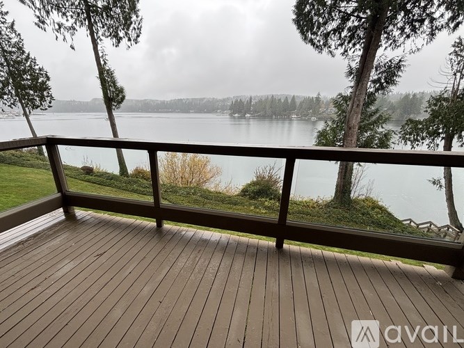 A wooden deck overlooks a lake with trees and a cloudy sky.