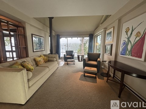 A living room with a beige couch, a chair, and a painting on the wall.