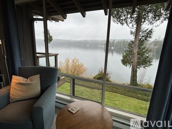 A cozy room with a view of a lake and trees.
