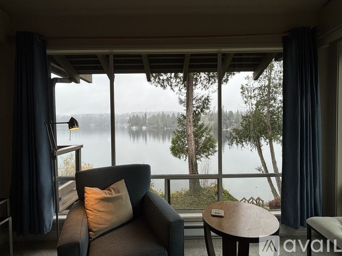 A living room with a couch, a table, and a view of a lake.