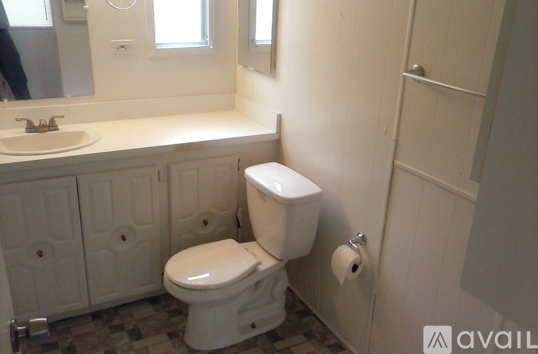A white toilet in a bathroom with a mirror above it.