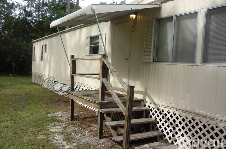 A mobile home with a wooden staircase leading to the door.