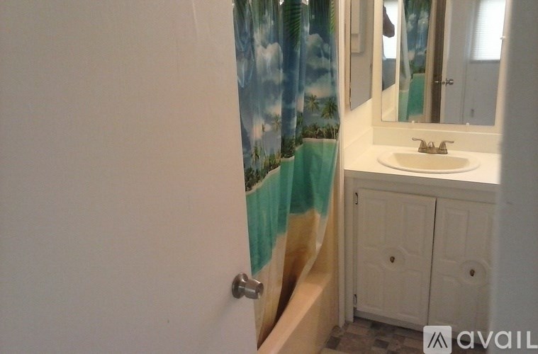 A bathroom with a white sink and a shower curtain with a beach scene on it.