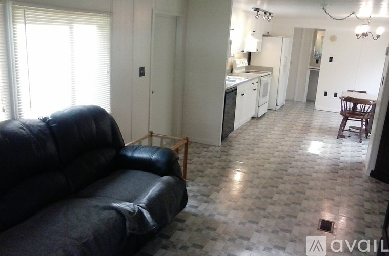 A black leather couch sits in a kitchen with a tiled floor.