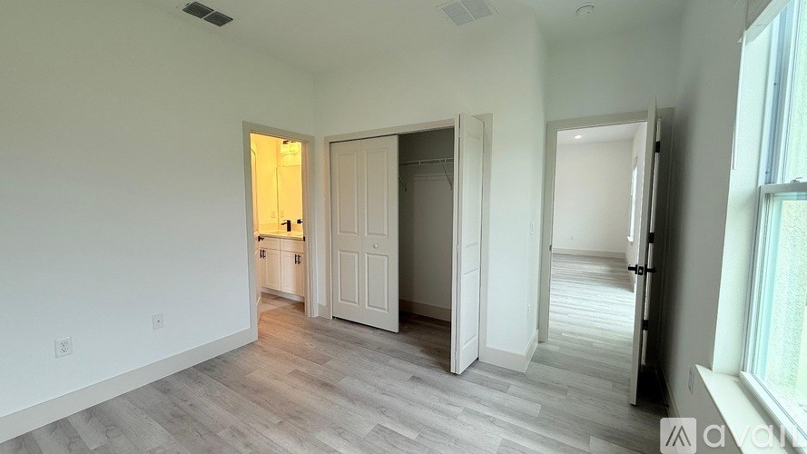 A spacious room with a kitchenette in the background and a doorway leading to another room.