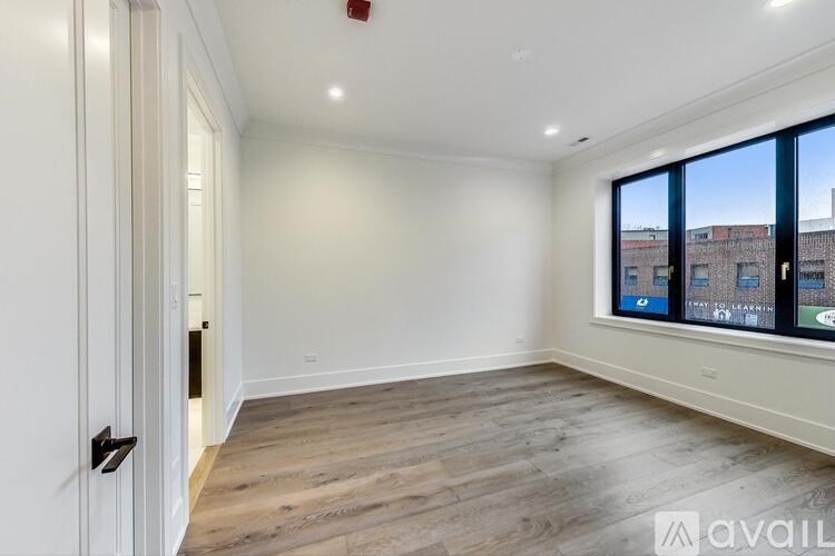 A spacious room with wooden flooring and a large window overlooking a cityscape.