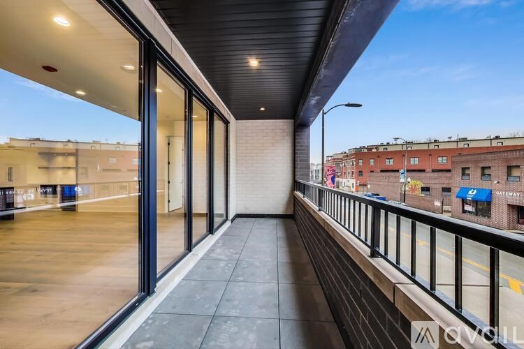 A balcony with a black railing and a view of a street with buildings.