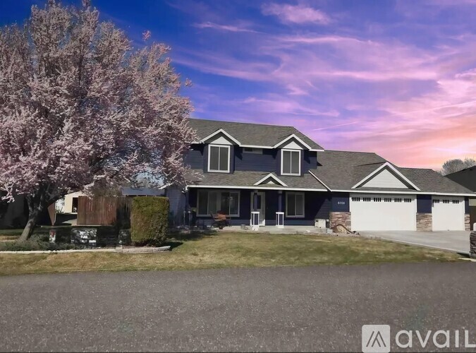 A house with a tree in bloom in front of it.