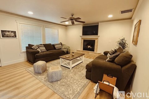 A living room with a brown couch, a white coffee table, and a fireplace.