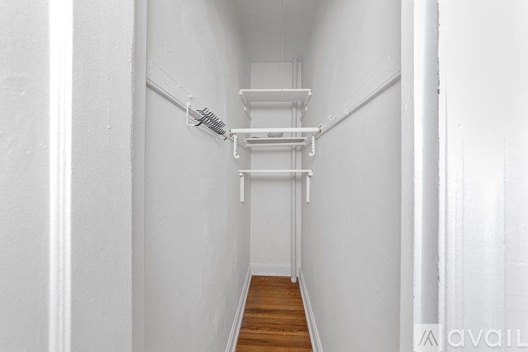 A long hallway with a white wall and a wooden floor.