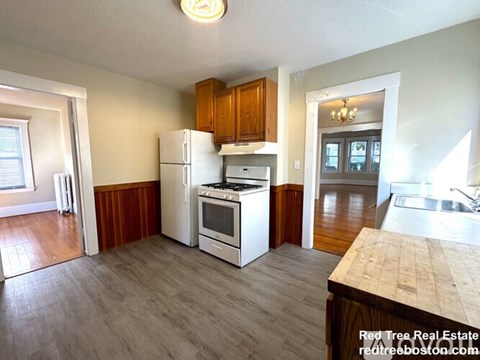 A kitchen with white appliances and wooden cabinets.