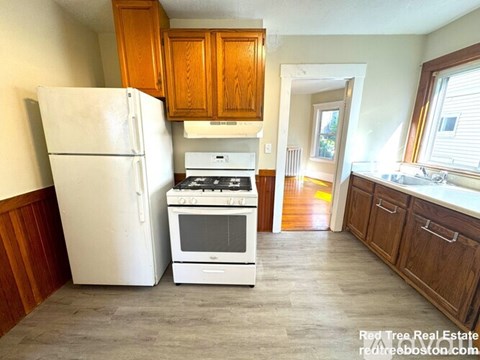 A kitchen with a white fridge, white stove, and wooden cabinets.