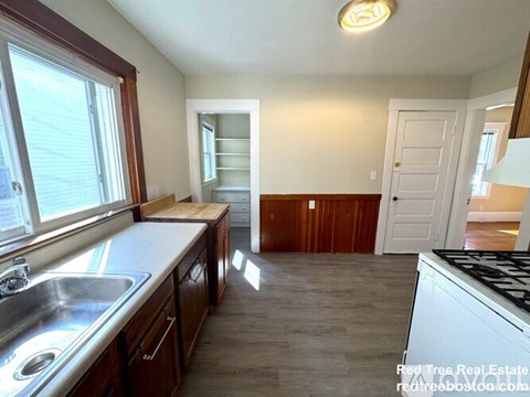 A kitchen with wooden cabinets and a white stove top oven.