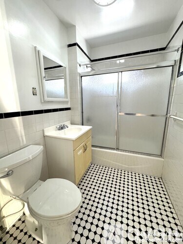 A white toilet sits in a bathroom with a black and white checkered floor.