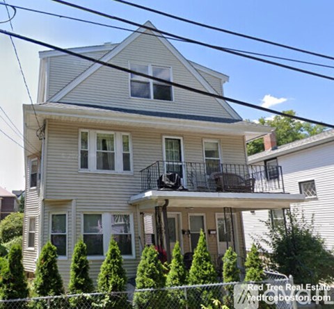 A two-story house with a balcony and a fence in front.