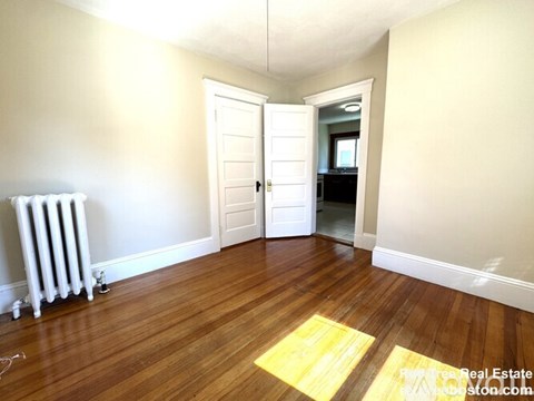 A room with a white door and a radiator on the floor.